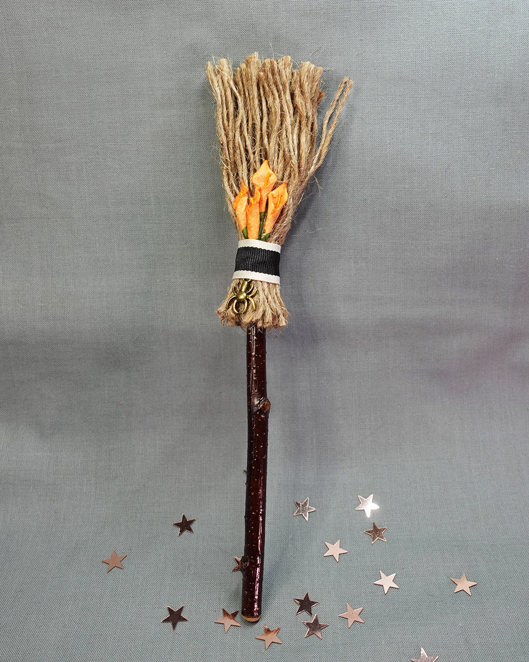 Decorative broom with orange lilies and spider on a gray background