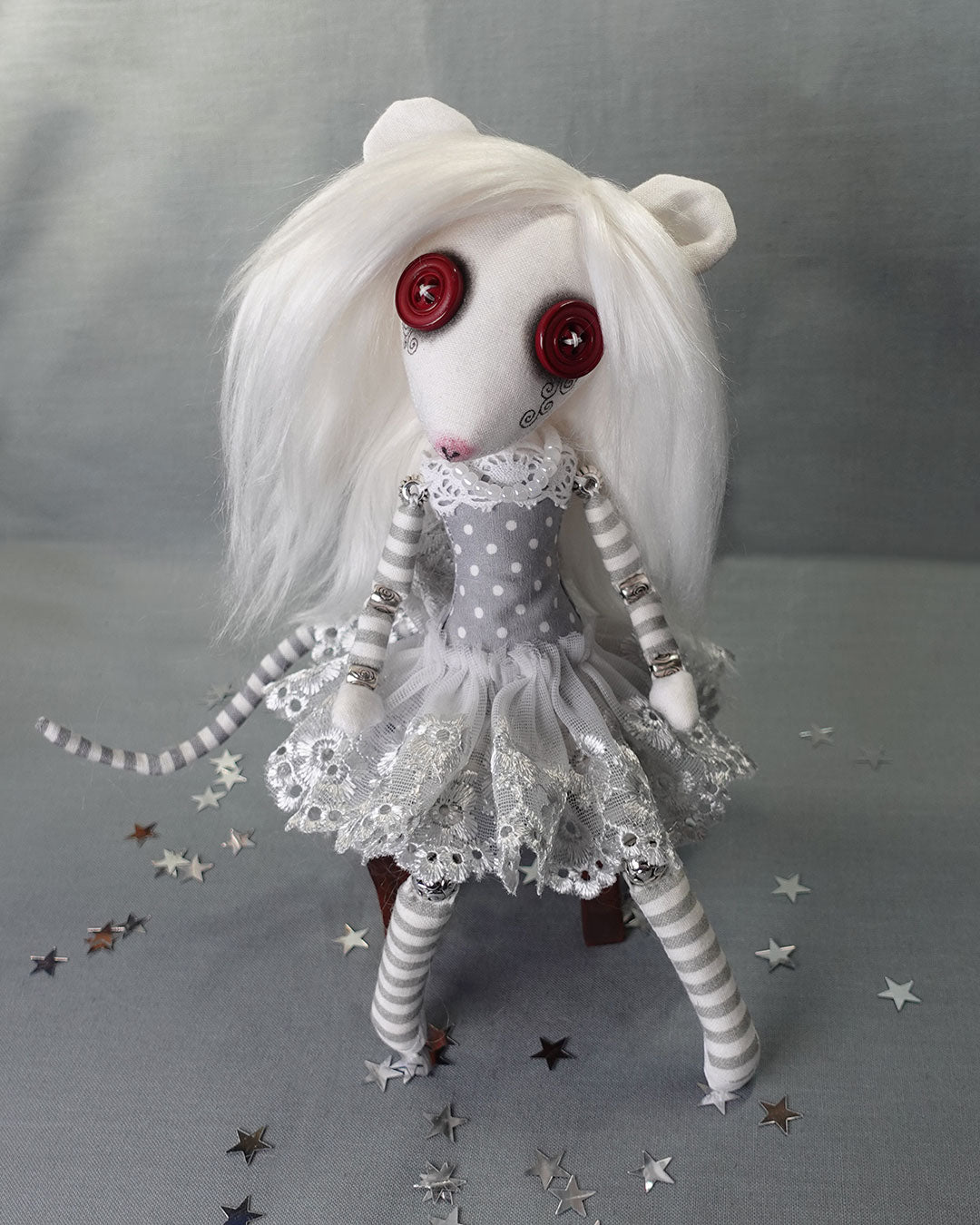 an albino rat cloth art doll with red button eyes and long white hair