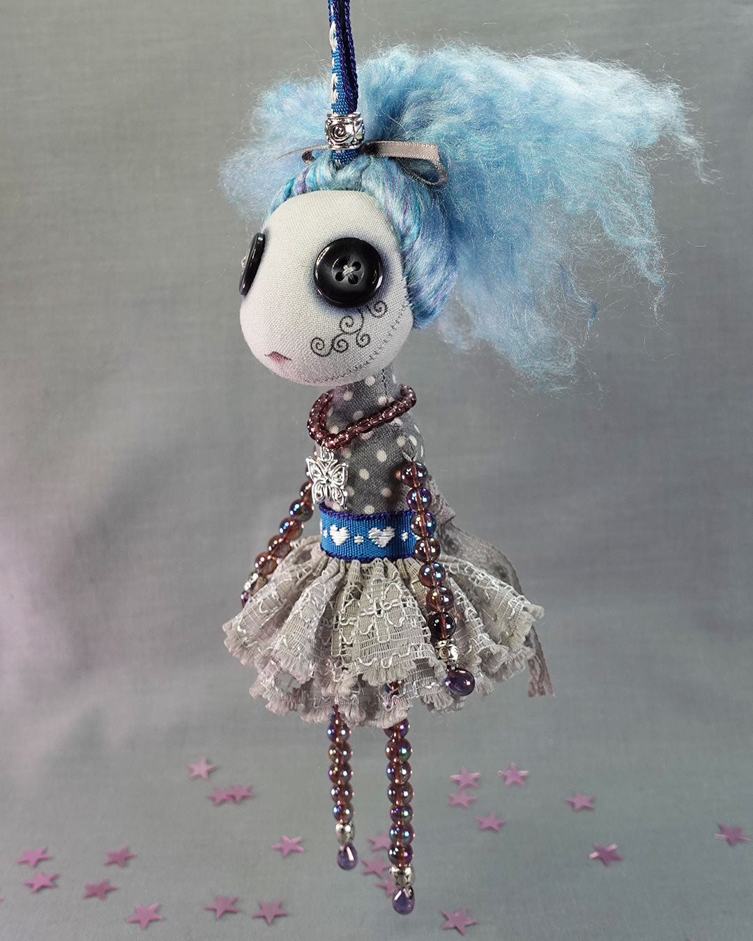 a hanging button eyed art doll with blue hair and purple glass beaded limbs