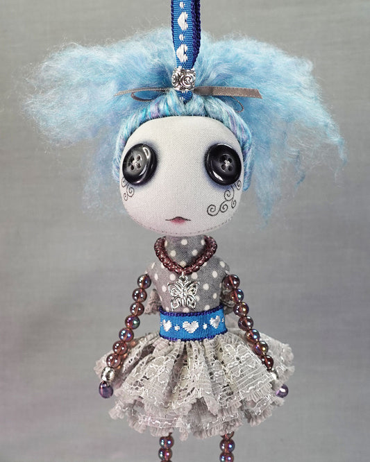 a hanging button eyed art doll with blue hair and purple glass beaded limbs