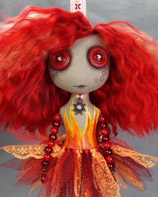 Close up of a fire spirit art doll in red and orange with painted flame detail