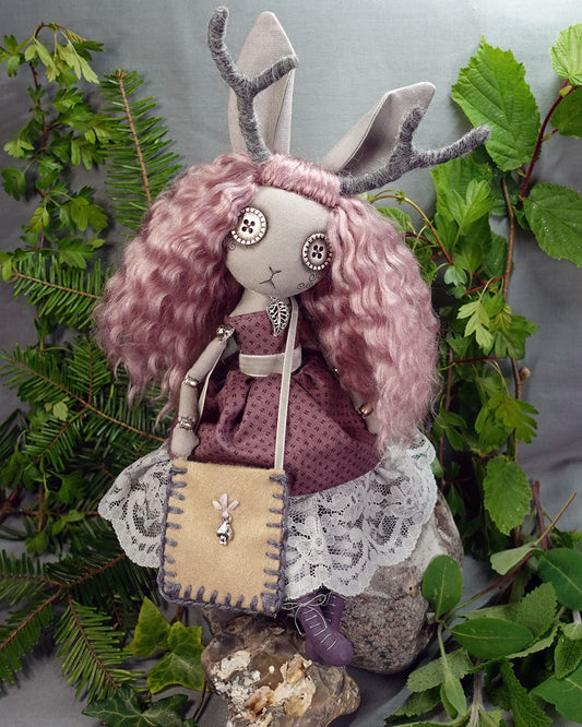 a jackalope art doll with button eyes in dusky rose pink dress with hand stitched foraging bag and lace up boots