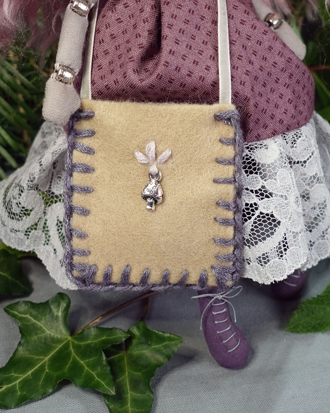 buff coloured felt bag with blanket stitch detail and mushroom charm