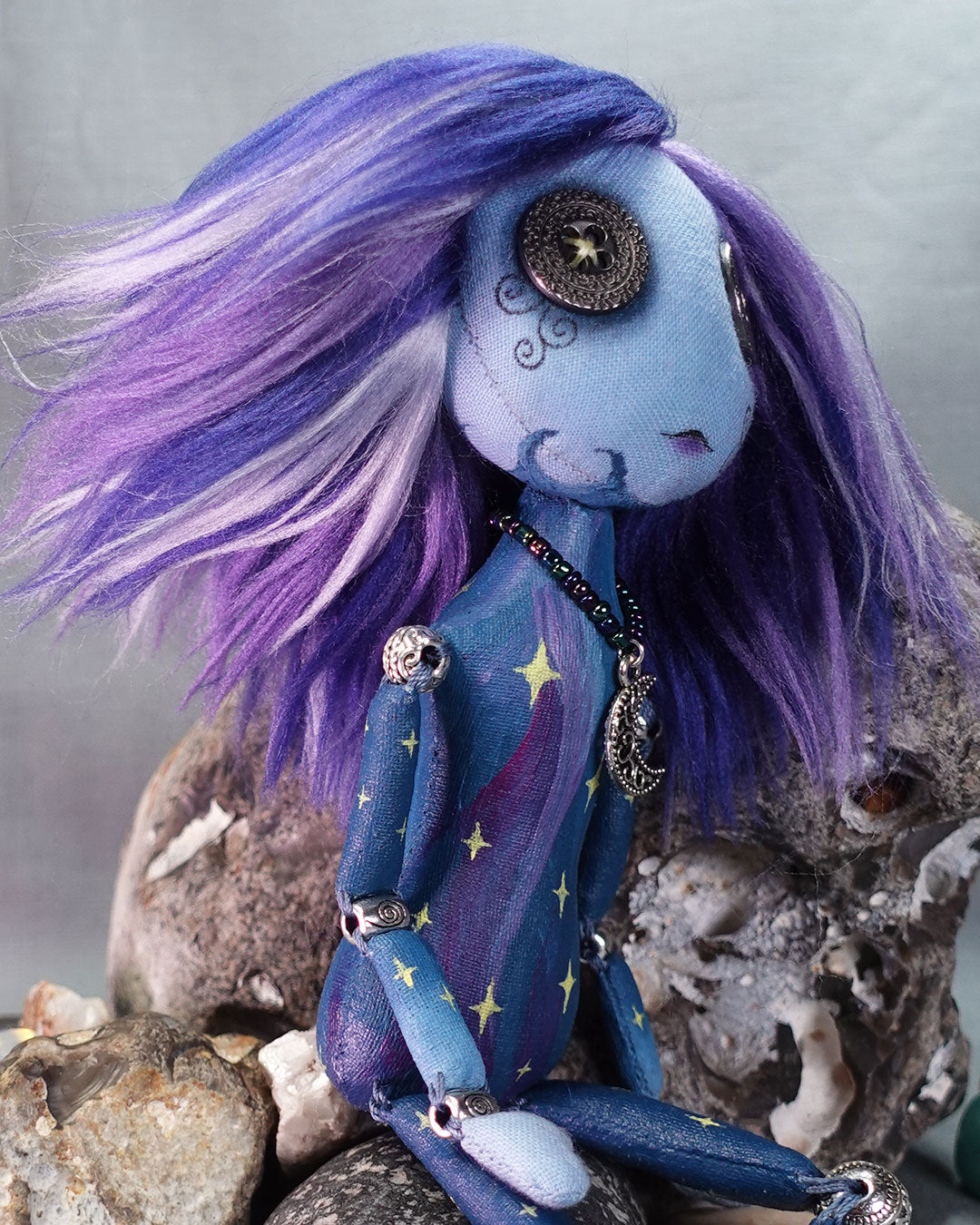 A bead jointed art doll painted as a starry sky in blues and purples