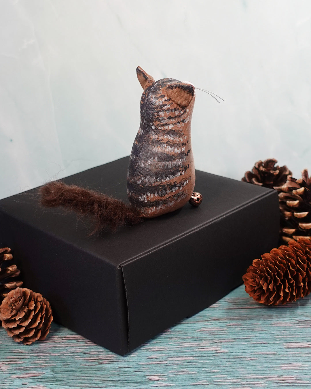 textile tabby cat figure with bushy tail on a dark surface.