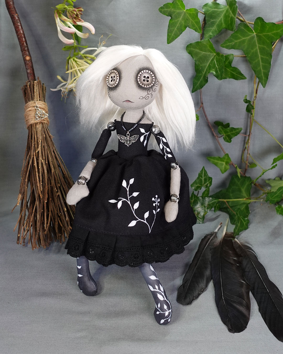 a gothic style cloth doll with white hair and black dress with hand painted vines