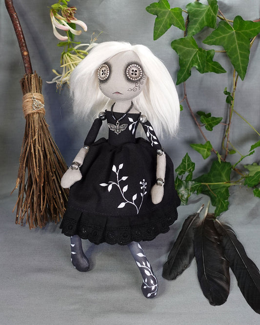 a gothic style cloth doll with white hair and black dress with hand painted vines