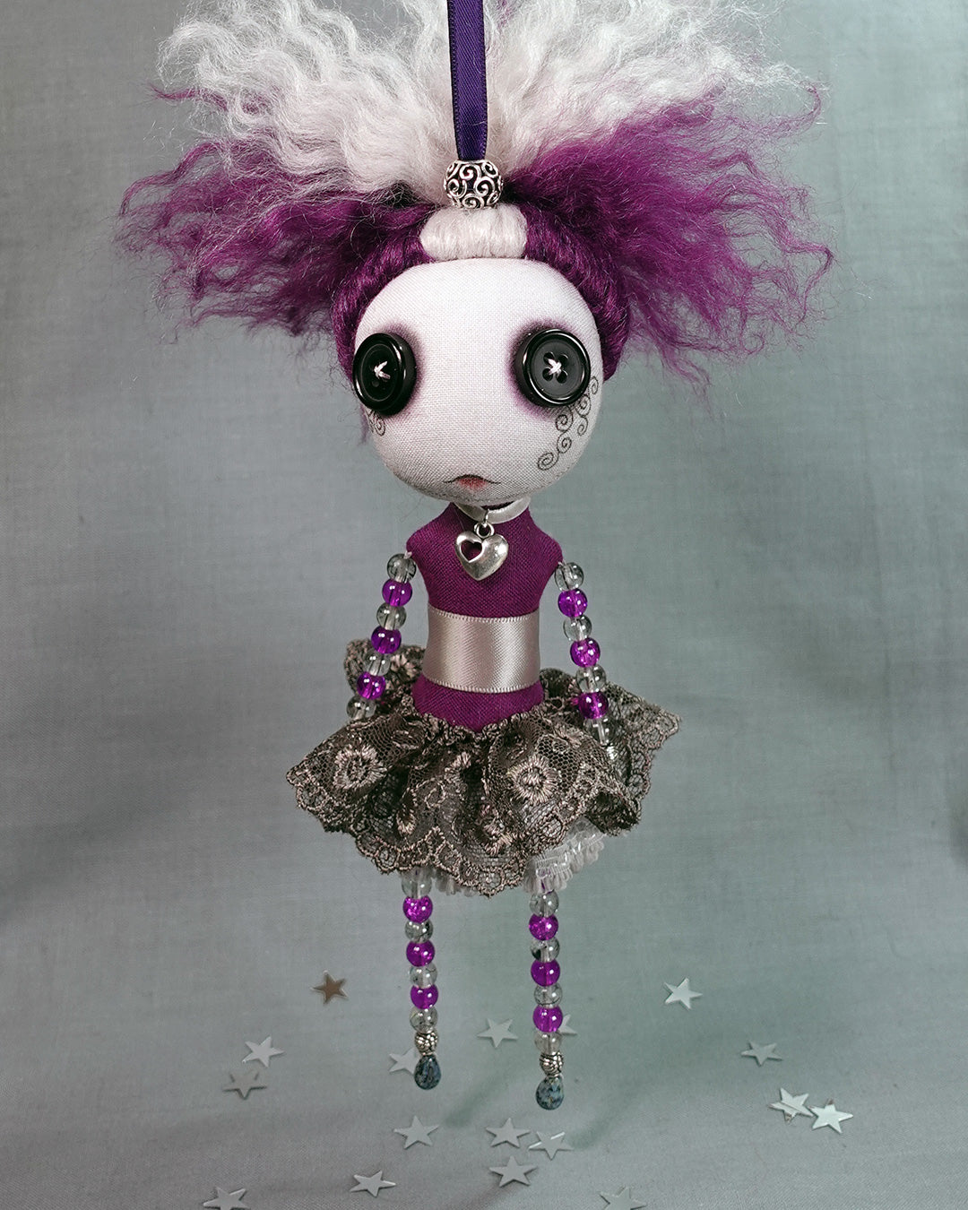 a beaded hanging cloth art doll with button eyes and purple hair