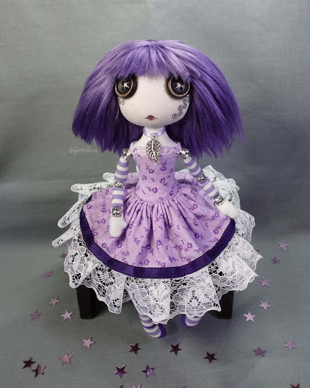 a button eyed cloth art doll with purple hair and dress