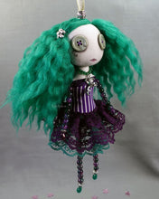 a hanging beaded cloth art doll with button eyes and green hair, in green and purple dress