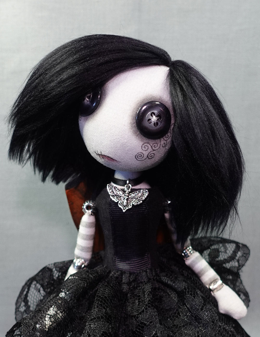 a button eyed gothic cloth doll with black hair and moth necklace