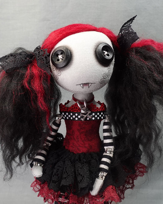 close up of a button eyed cloth vampire doll in black and dark red