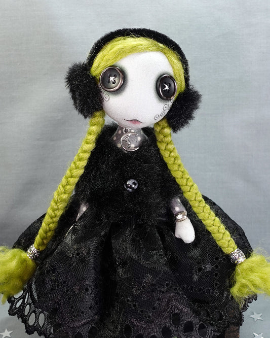 a Goth winter art doll with green hair and faux fur earmuffs