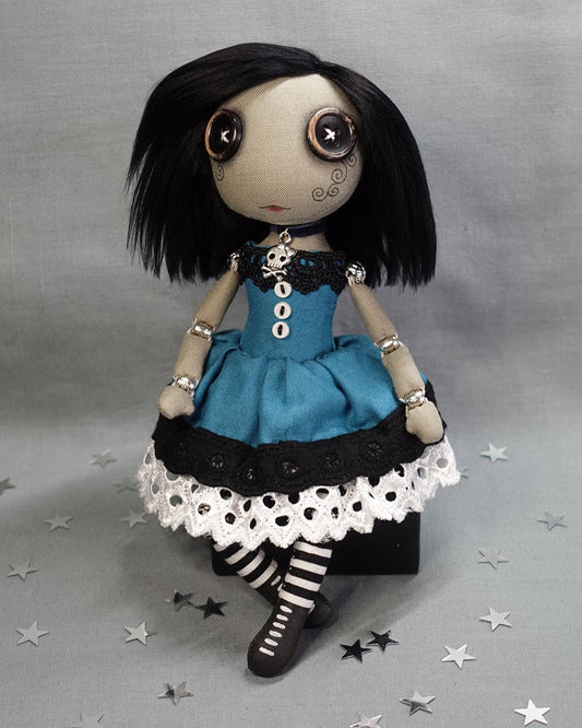 a button eyed cloth art doll with black hair in blue dress with striped legs and lace up boots