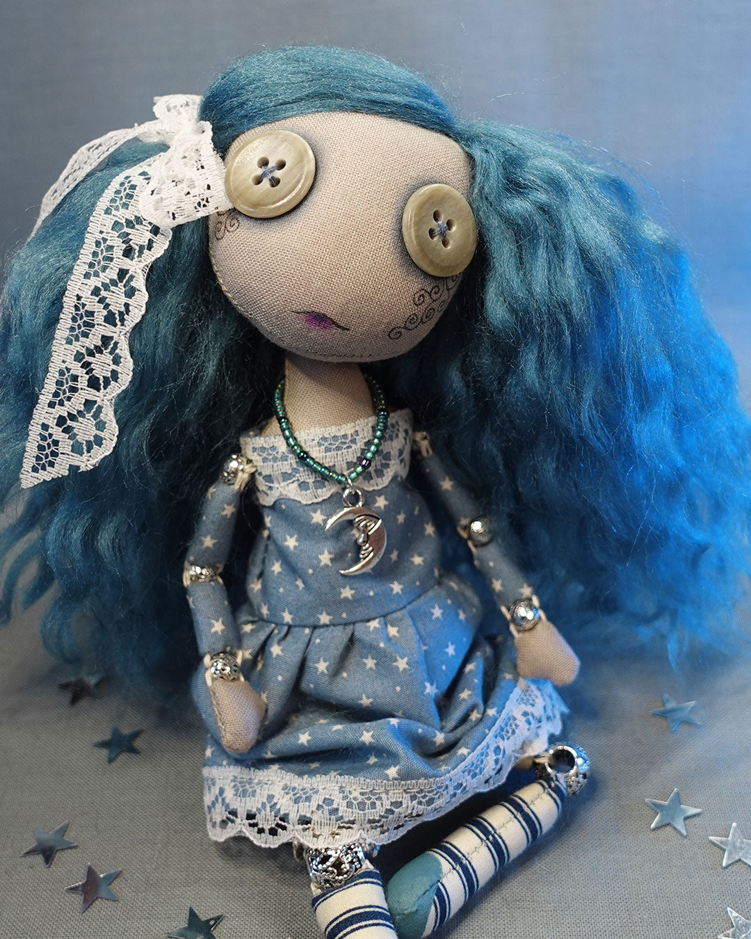 a button eyed cloth art doll with blue hair in star print dress