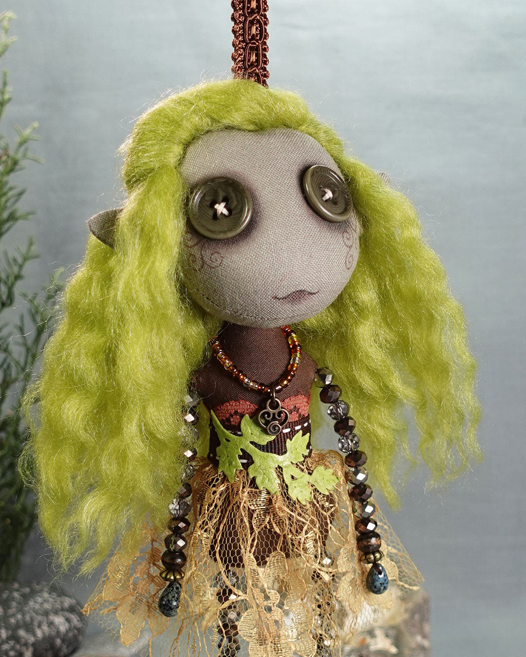 a hanging gnome art doll with button eyes and elf ears in greens and browns