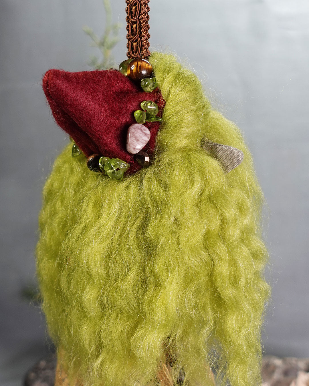 doll with green hair and pointed red hat with beads and gem stones