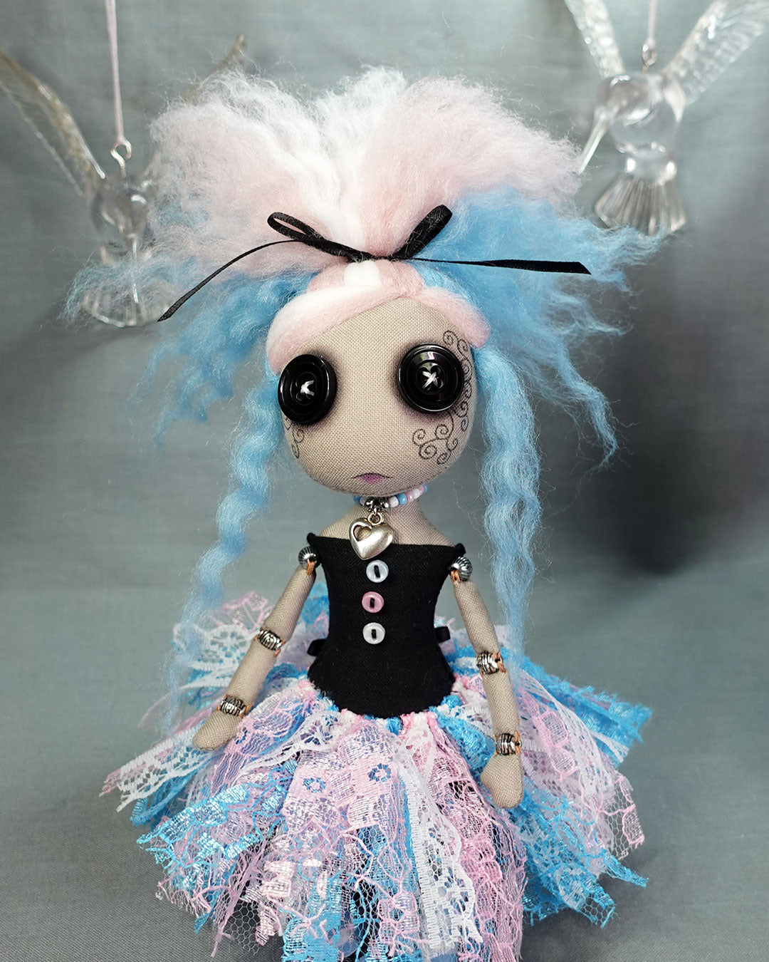 close up of a button eyed cloth art doll in trans flag colours