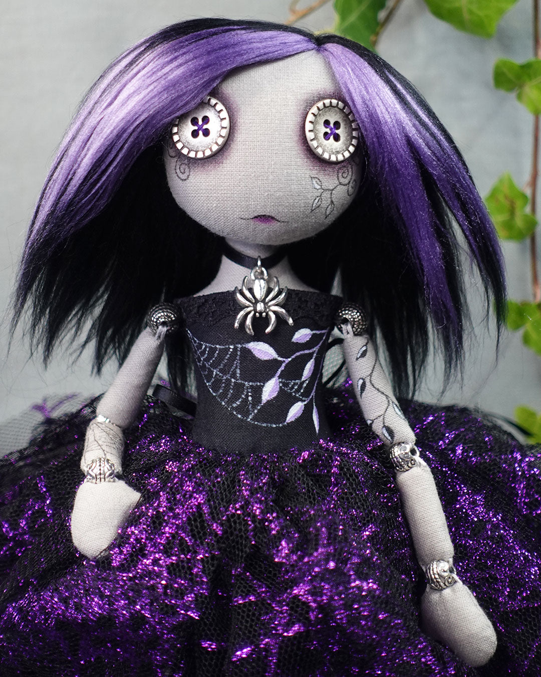 Art doll with purple and black hair, dressed in a black and purple outfit with spider web design.