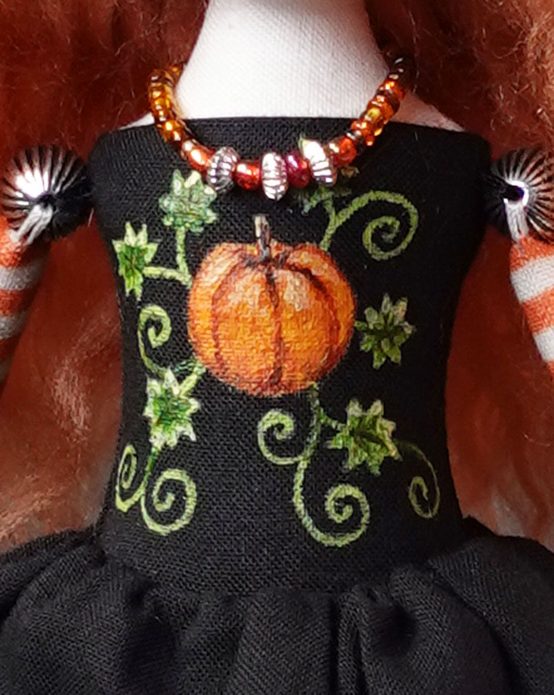 Black dress with pumpkin design and bead necklace on front of doll