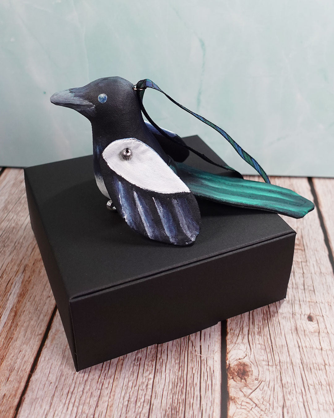 magpie bird ornament sitting on black box