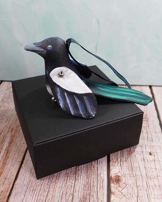 magpie bird ornament sitting on black box