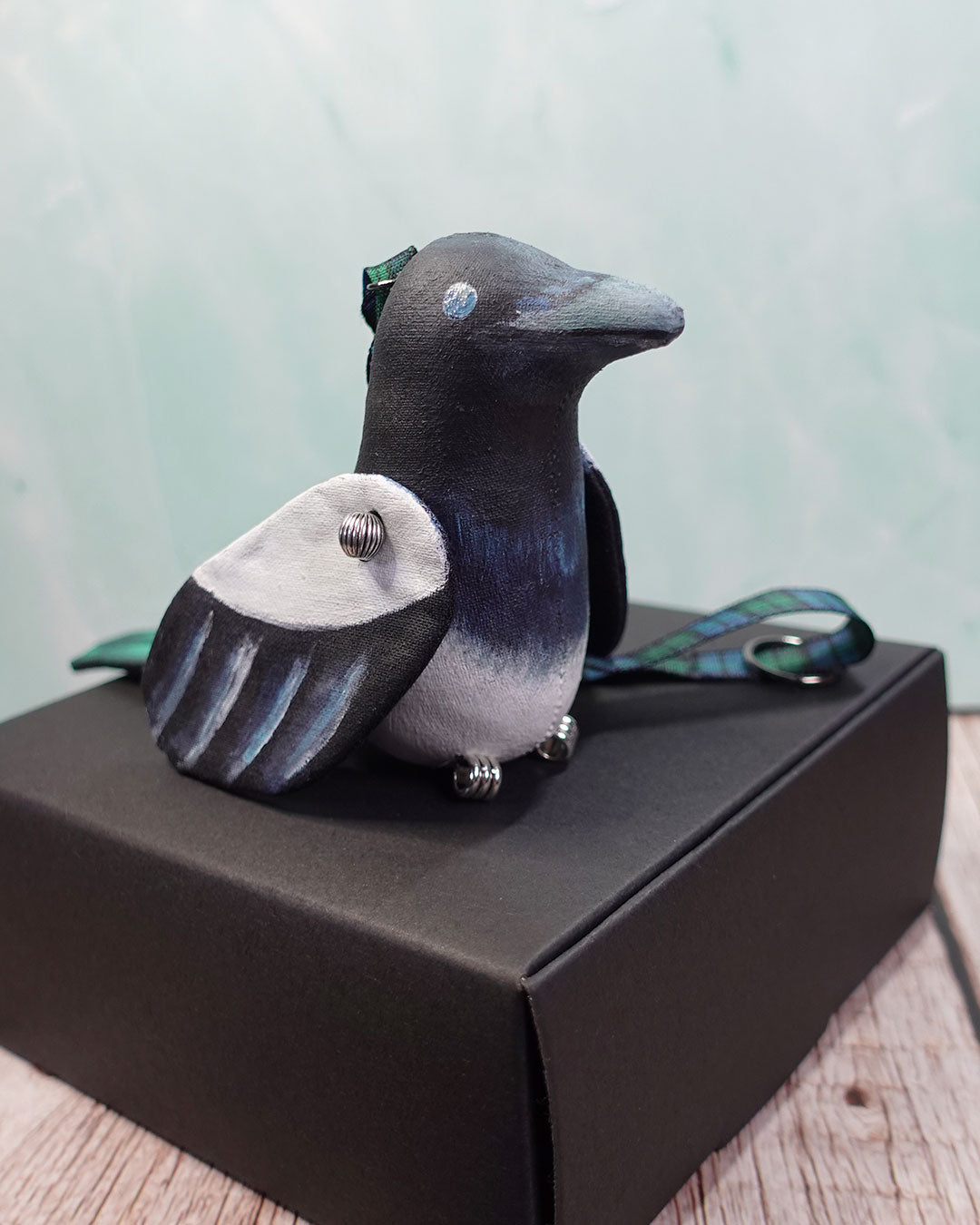 magpie textile soft sculpture sitting on black box
