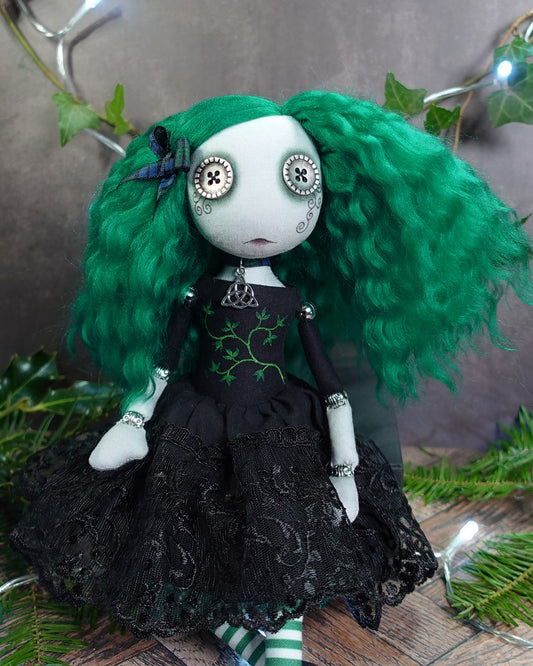 a button eyed girl doll with green hair and black dress with green leaves