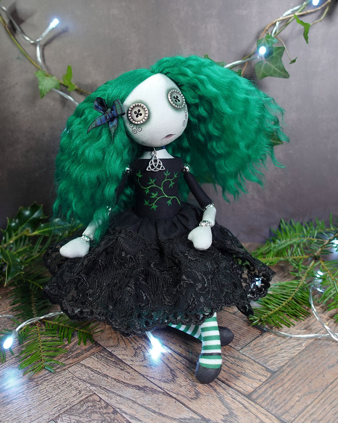 a button eyed girl doll with green hair and black dress with green leaves
