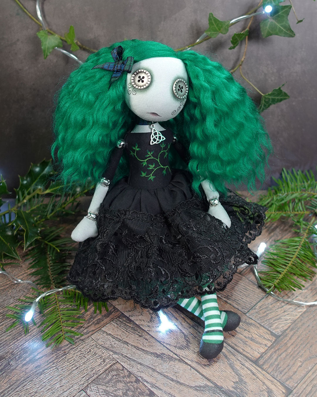 a button eyed girl doll with green hair and black dress with green leaves