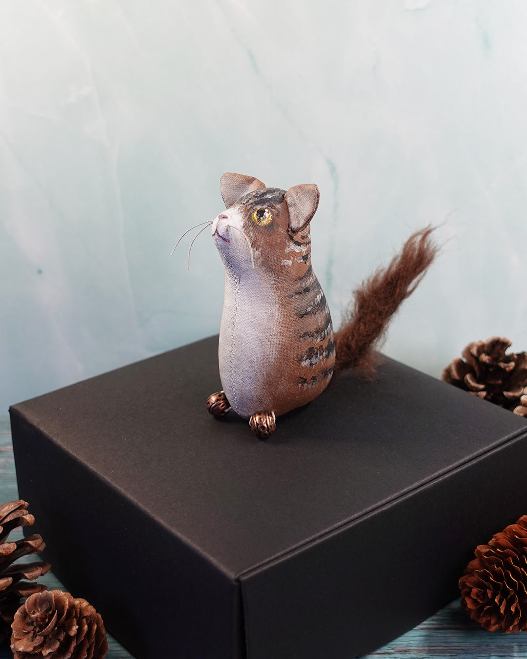 textile tabby cat figure with bushy tail on a dark surface.