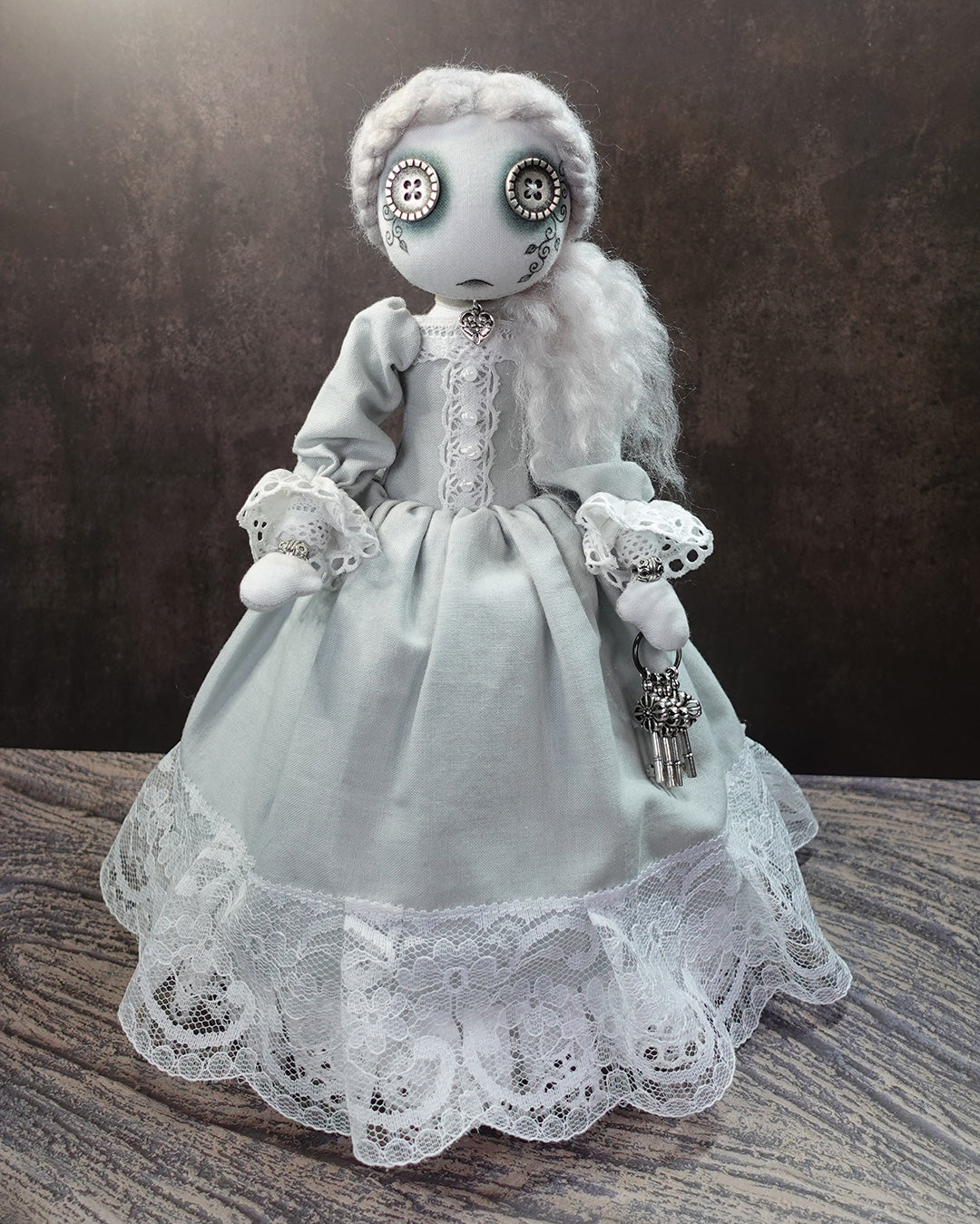 Pale ghost art doll in victorian style gown holding silver keys