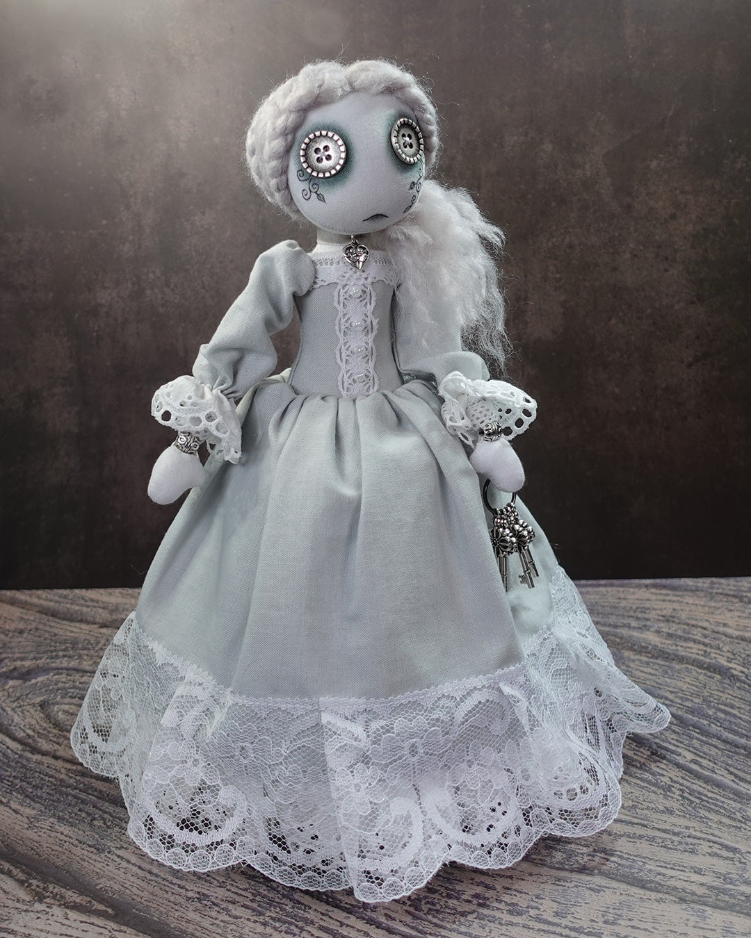 Textile doll in a light grey victorian gown with white lace detail.