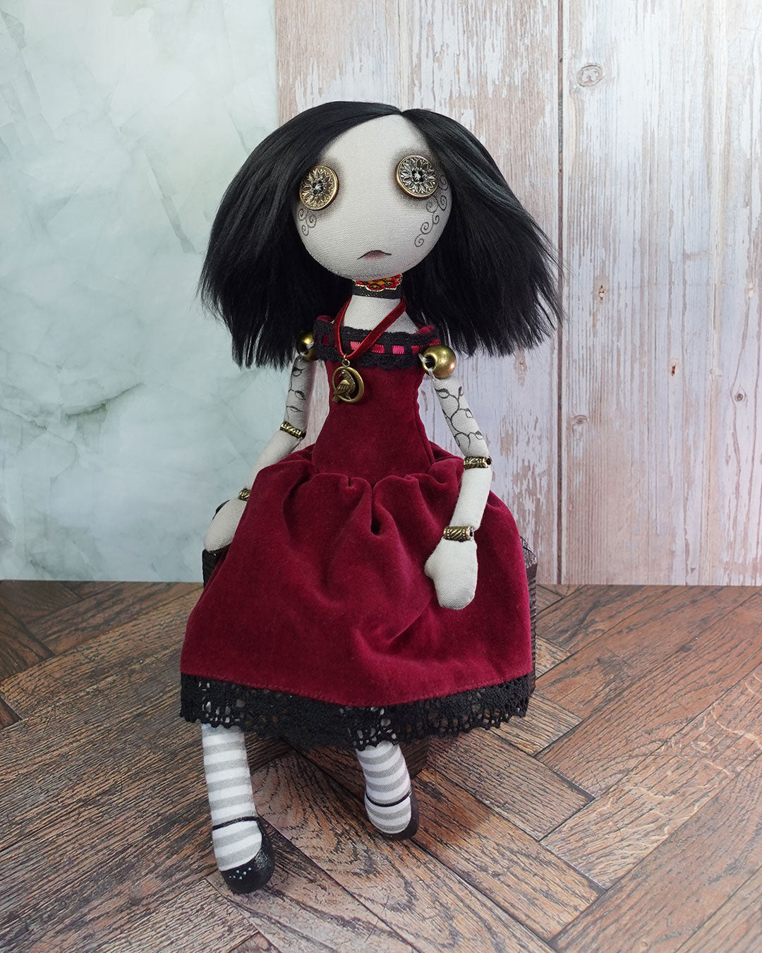 Textile doll with button eyes, black hair and red velvet dress