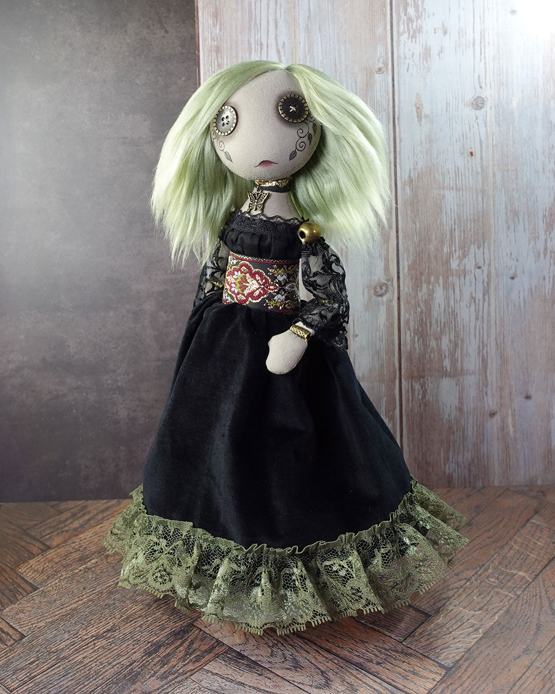 Art doll with green hair and black dress on a wooden floor