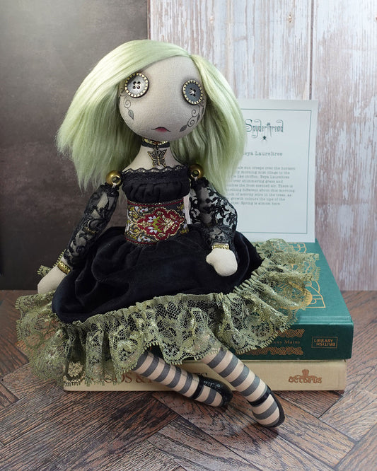 Art doll with green hair and intricate clothing with story card in background