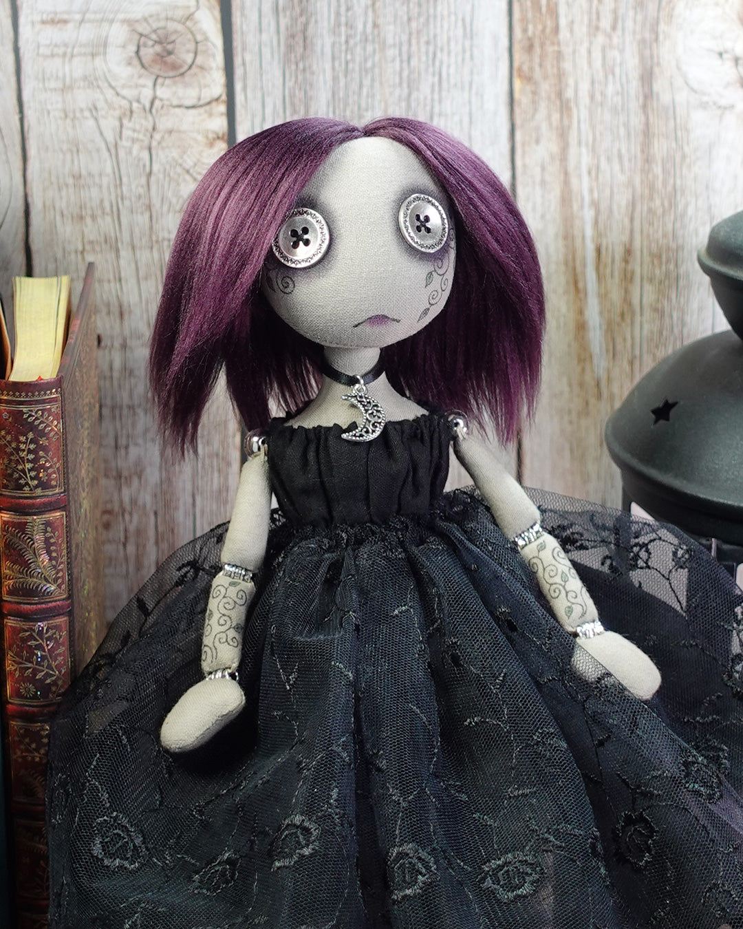 Gothic-style doll with purple hair and black dress against a wooden background