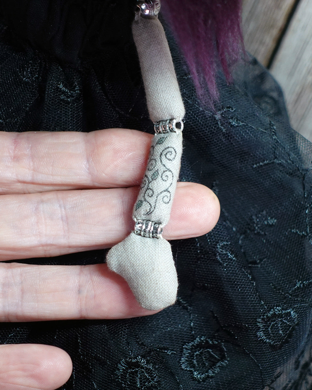 close up of tattoos on art dolls arm, held by the artist's hand